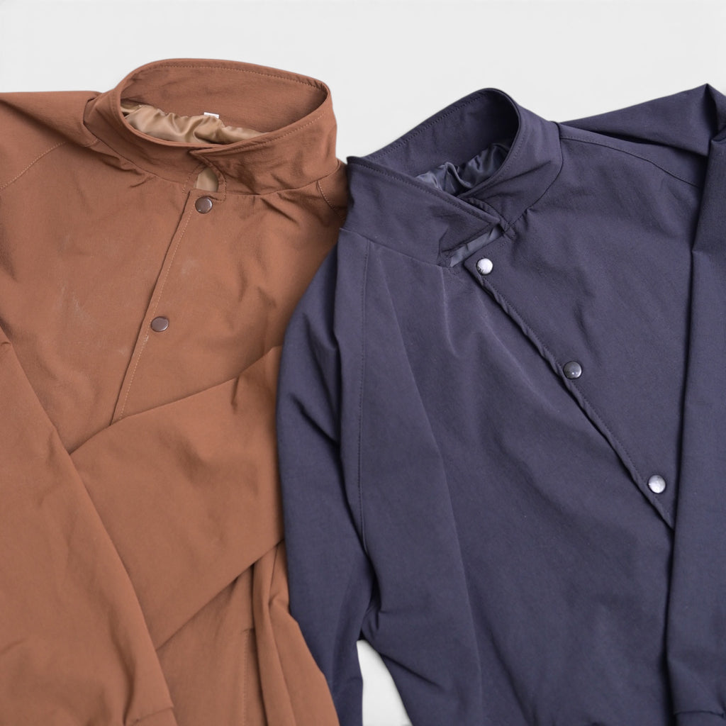 Button varsity jacket in brown and navy blue with snap buttons, flat lay